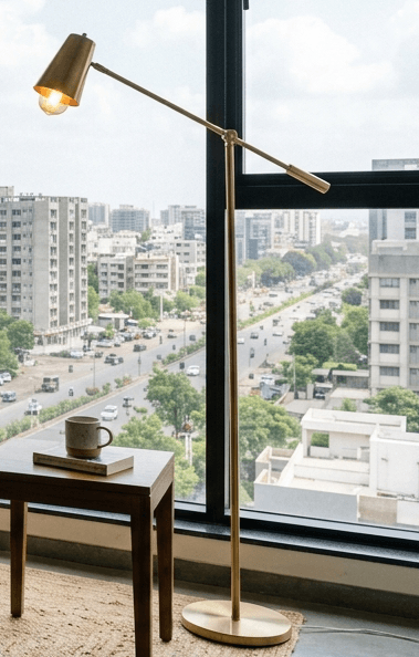 Aksh Floor Lamp with turned teak stem and spun brass base casting warm light